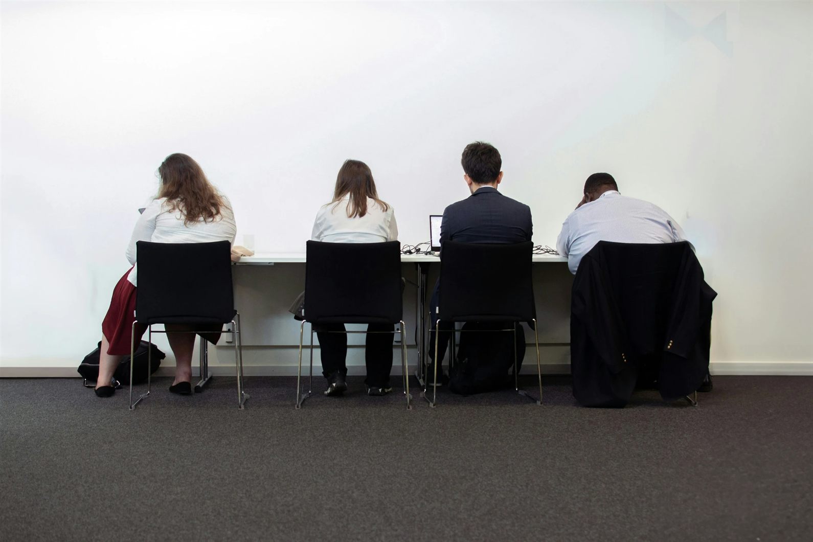 Candidates waiting in a row at an office desk